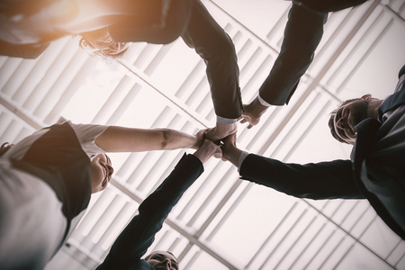 Low angle view of happy businesspeople giving high five to each other in office premisesの写真素材
