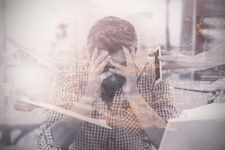 Stressed out businessman at work in office with colleagues holding mobile phone and documentsの写真素材