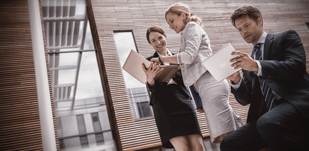 Businesspeople using laptop and tablet in office premisesの写真素材