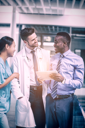 Nurse and doctor having discussion with businessman in hospitalの写真素材