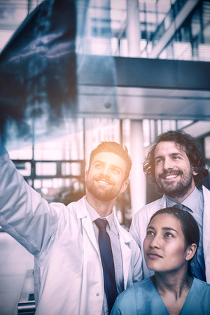 Doctors and nurse examining X-ray report in hospitalの写真素材