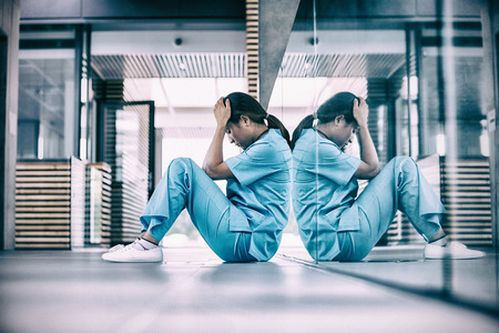 Stressed nurse sitting in hospital corridorの写真素材