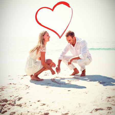 happy couple drawing heart shape at beachの写真素材