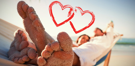 Close up of sandy feet of couple in a hammock against printの写真素材