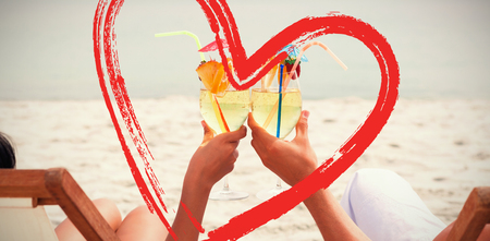Couple clinking glasses of cocktail on beach against printの写真素材