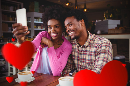 Hearts against happy young couple taking selfie in cafeteria 3Dの写真素材