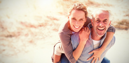 Portrait of laughing couple standing at beach on sunny dayの写真素材
