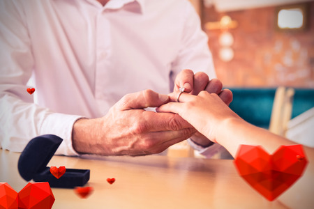 Hearts against man putting engagement ring on womans finger 3D