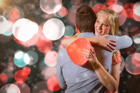 Couple embracing each other while holding gift against digitally generated twinkling light designの写真素材