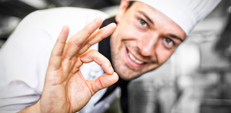 Closeup portrait of a smiling male cook gesturing okay sign in the kitchenの写真素材