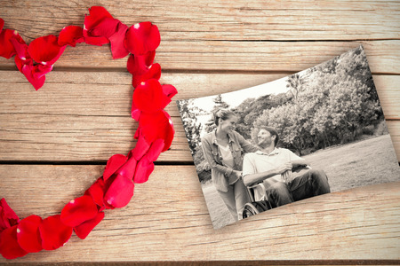 flower heart against smiling man in wheelchair talking with partnerの写真素材