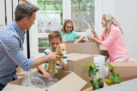 Parents and kids unpacking carton boxes in living room at new homeの写真素材