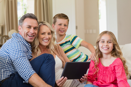 Parents and kids using digital tablet in living room at home