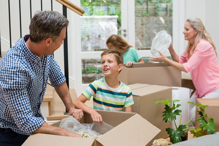 Parents and kids unpacking carton boxes in living room at new homeの写真素材