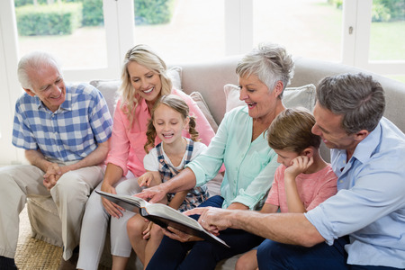 Multi-generation family looking at their album photo in living room at home