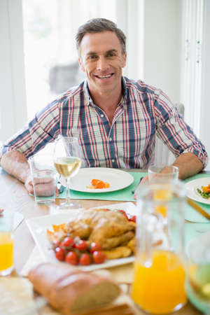 Portrait of happy man having meal on dinning table at homeの写真素材