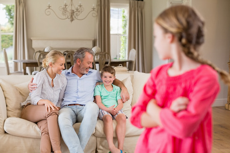Girl looking at back at family sitting on sofa in living roomの写真素材