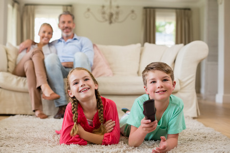 Family and kids watching television while having popcorn in living room at home