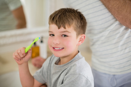 Portrait of boy brushing teeth in bathroom at homeの写真素材
