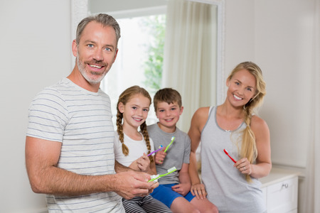 Portrait of smiling parents and kids brushing teeth in bathroom at homeの写真素材
