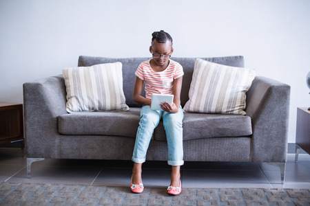 Girl sitting on sofa using digital tablet in hospital corridorの写真素材