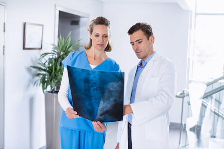 Two doctors looking over patients x-ray in corridor at hospital