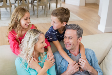 Smiling parents and kids looking face to face in living room at home