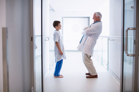 Doctor talking to boy patient in hospital corridorの写真素材