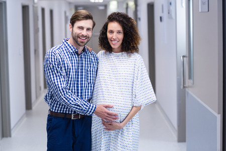 Portrait of happy couple standing in corridor of hospitalの写真素材