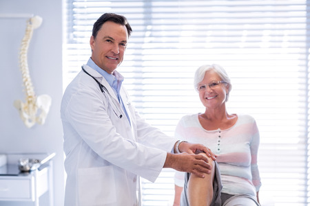 Portrait of physiotherapist giving knee therapy to senior woman in clinic Portrait of physiotherapist giving knee therapy to senior woman in clinic