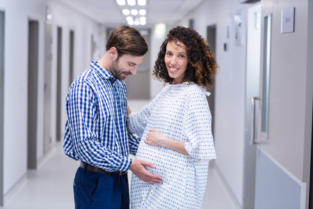 Man comforting pregnant woman in corridor of hospitalの写真素材