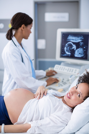 Doctor doing ultrasound scan for pregnant woman in hospitalの写真素材