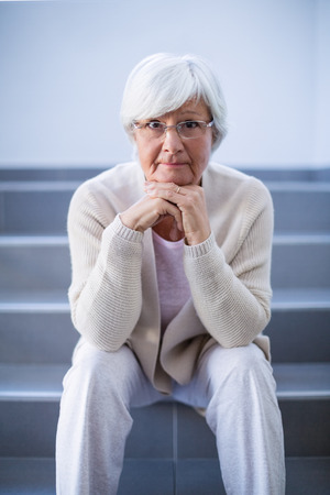 Portrait of senior woman sitting on stairs in hospitalの写真素材