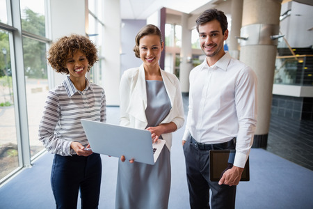 Portrait of business executives holding laptop at conference centreの写真素材