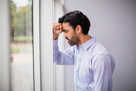 Worried and stressed businessman with hand on head at conference centre