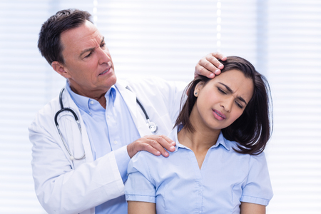 Doctor examining female patients neck in clinicの写真素材