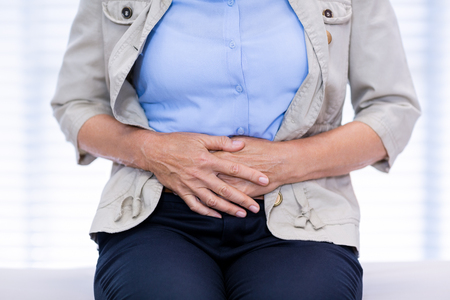 Mid section of female patient suffering from stomach ache in clinicの写真素材