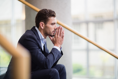 Worried businessman sitting on steps at conference centreの写真素材