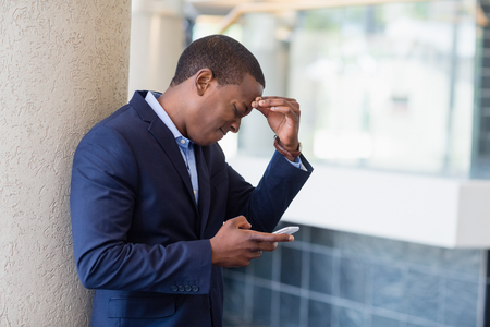 Worried businessman looking at mobile phone in conference centreの写真素材