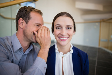 Businessman whispering something to his colleague at conference centreの写真素材