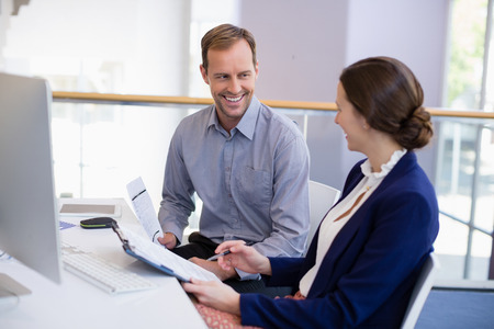 Businesswoman working at desk with colleague in conference centreの写真素材