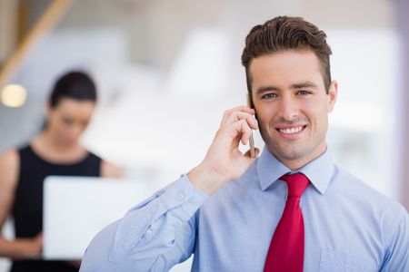 Portrait of businessman talking on mobile phone at conference centreの写真素材