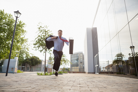 Businessman holding briefcase running outside the conference centreの写真素材
