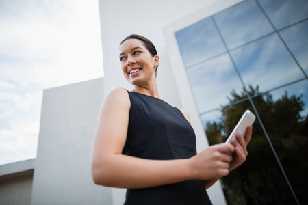 Businesswoman using mobile phone outside the conference centreの写真素材