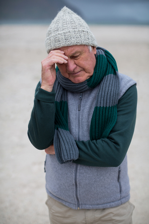 Thoughtful senior man standing on the beachの写真素材