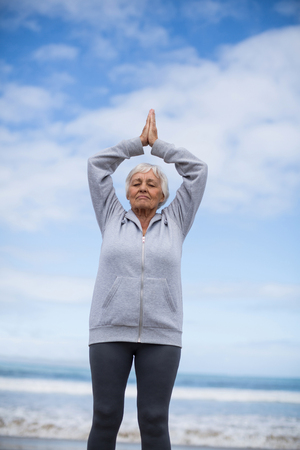 Senior woman doing meditation on the beachの写真素材