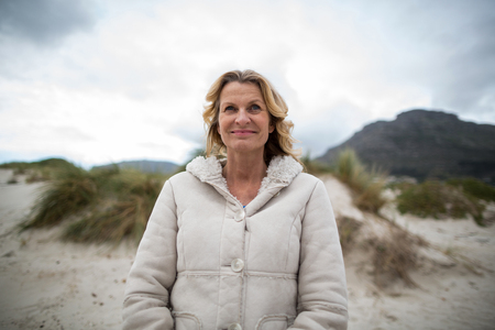 Smiling mature woman standing on the beachの写真素材