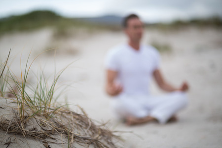 Mature man doing meditation on the beach