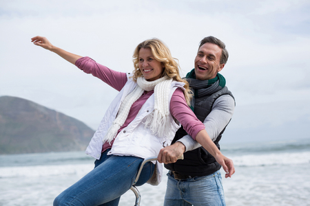 Happy mature couple riding bicycle on the beachの写真素材