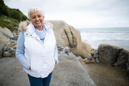 Portrait of smiling senior woman standing on the beachの写真素材